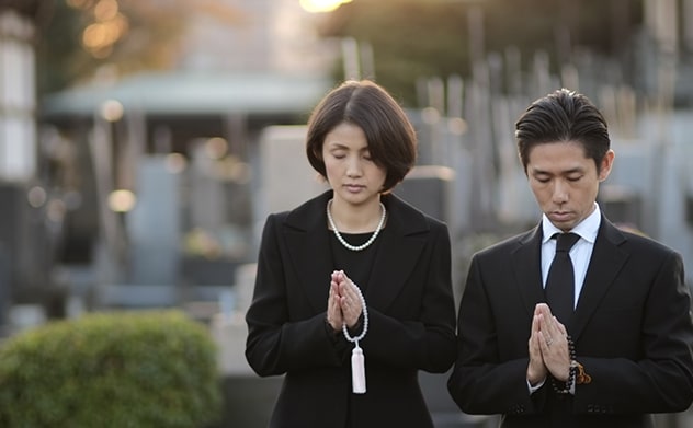 お墓参りする喪服の男女